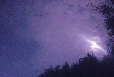 The Moon in cloudy sky with stars and trees